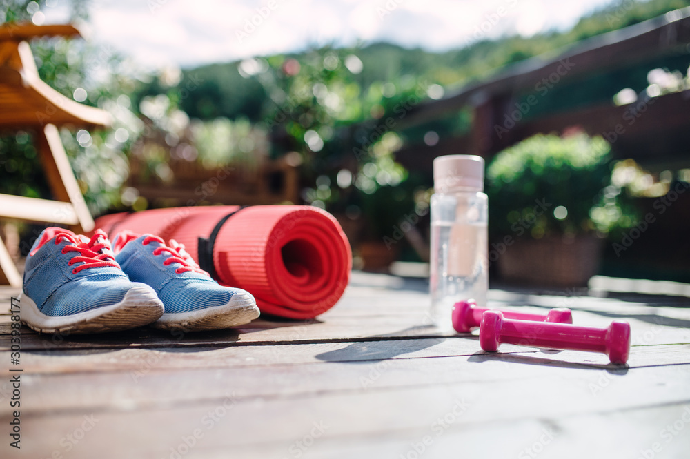 Water bottle, trainers and dumbbells outdoors on a terrace in summer. Water bottle, trainers and dumbbells outdoors on a terrace in summer.