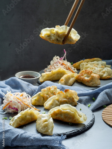 Mandu or Gyoza serve on black butcher stone with soy sauce and chopstick, chinese food style for food issue. photo