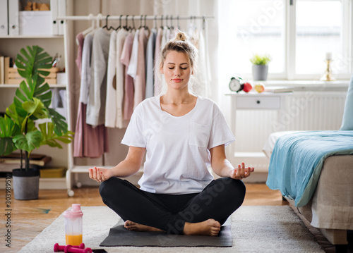 Young woman doing yoga exercise indoors at home, meditating.