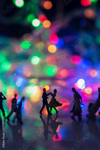 Miniature toy - A couple dancing on the street together among busy commuters crowd with colorful bokeh lights, happiness concept.
