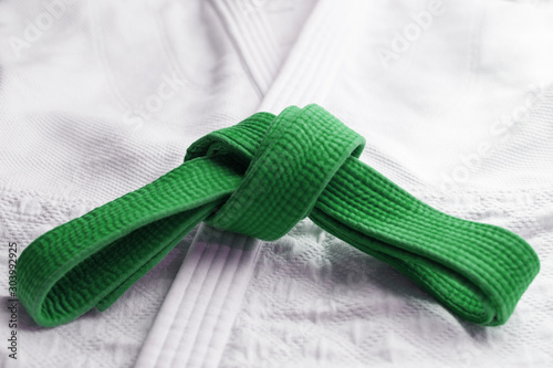 Green martial art belt tied in a knot on white gi in background
