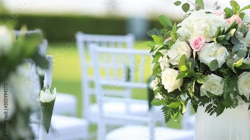 Many bouquet of flower decorate for wedding ceremony event, set on white pole near chairs for make the way of couple