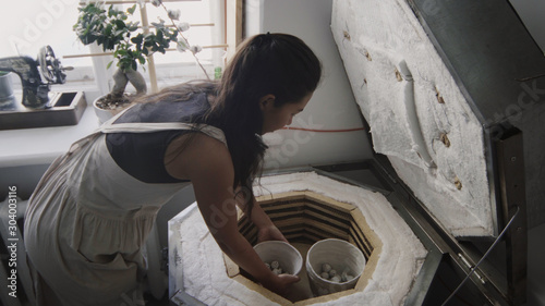 Εκτύπωση καμβά Asian female potter take raw clay pot and put it into a kiln for firing
