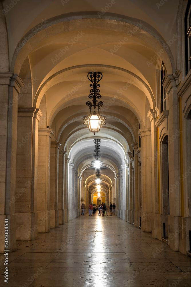 Arched and lit passageway next to the Arco da Rua Augusta in the Baixa district, Lisbon's historical centre, in the evening.