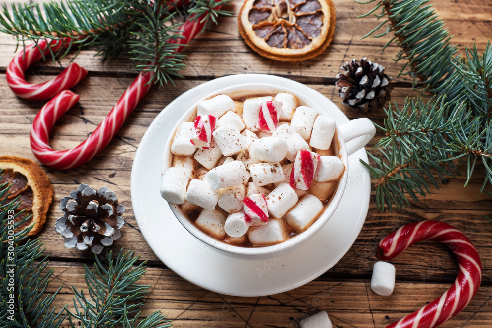 A Cup of hot chocolate with marshmallows. Christmas tree and decorations, cane caramel and oranges nuts Wooden background A Cup of hot chocolate with marshmallows. Christmas tree and decorations, cane caramel and oranges nuts Wooden background