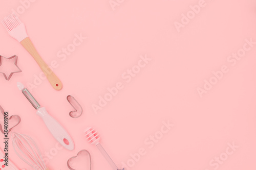 Various pink kitchen utensils on abstract pink background. Greater, whisk and iron cooking form. Top horizontal view copyspace love cookong concept