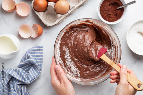 close up of female hands mixing ingredients in bowl. Baking chocolate cake photo