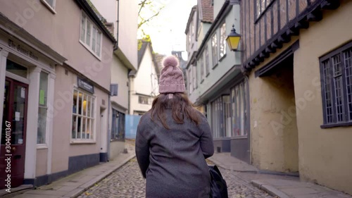 Woman Walking with her Back to the Camera on Elm Hill, one of The Medieval Streets of Norwich, England. photo