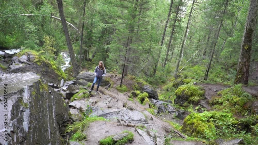 a young girl stands at the waterfall