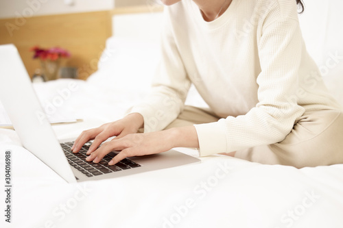 asian woman using laptop on bed