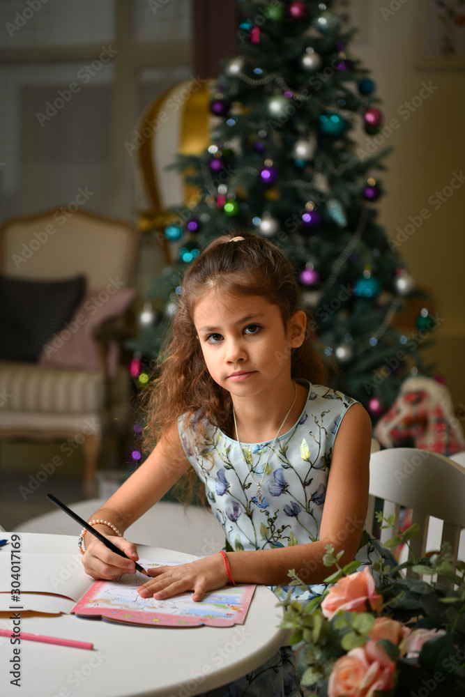 girl writes a letter to Santa Claus on the background of a Christmas tree