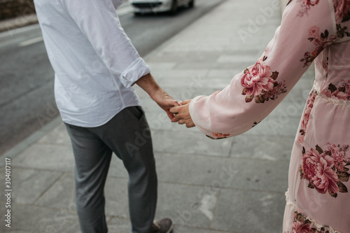 Close up view of young couple joining hands. Love, trust, family, partnership, happiness, goals. Holding hands on the street. 