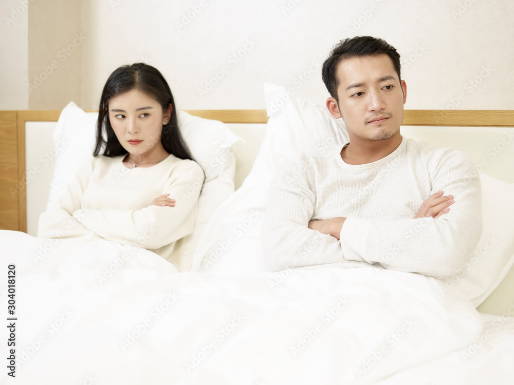 young couple sitting in bed angry with each other young couple sitting in bed angry with each other