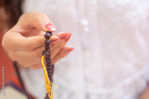 Εκτύπωση καμβά Religious Asian buddhist woman praying with hand holding rosary beads
