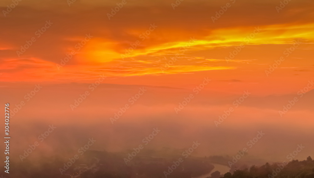 Fototapeta premium Mountain view panorama misty morning of top hill around with soft mist with orange sun light in cloudy sky background, sunrise at Wat Tha Ton, Fang, Chiang Mai, Thailand.