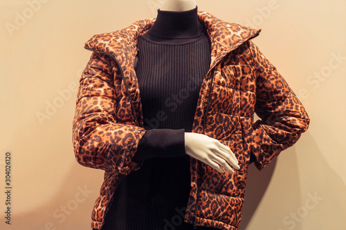 mannequin in a shop window behind glass wearing a black turtleneck and a leopard print jacket photo