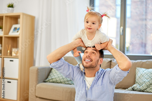 family  parenthood and fatherhood concept - happy father riding little baby daughter on his neck at home