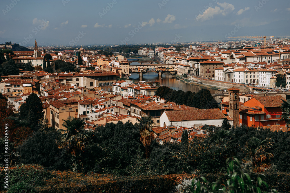 View of the city from the highest point of Florence from where you can see the famous Ponte Vecchio, residential buildings with orange roofs and the local river of the city | FLORENCE, ITALY - 14 SEPT