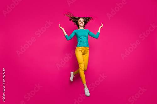 Full length body size photo of cheerful positive running girlfriend jumping throwing her hair up smiling toothily in teal shirt isolated fuchsia vivid color background