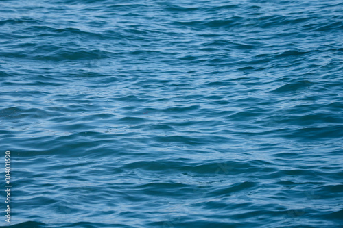 Blurred Natural Blue Background. Texture of blue sea water. Horizontal, cropped shot. Concept of nature and tourism.