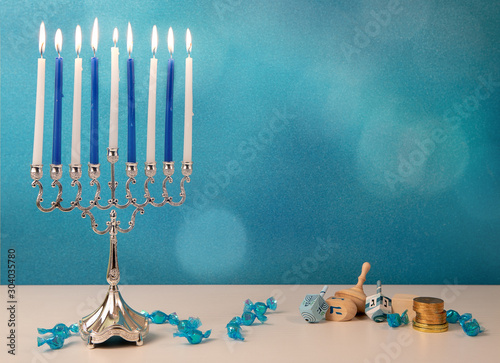 concept of of jewish religious holiday hanukkah with wooden spinning top toys (dreidel), traditional chandelier menorah and chocolate coins