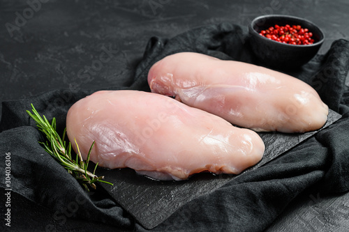 Raw chicken fillet on a cutting Board. Fresh Breasts. Black background. Farm organic meat.
