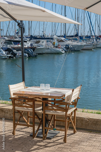 chairs and a table on the Mediterranean coast in the recreation area of ​​the port of the Italian capital © westermak15