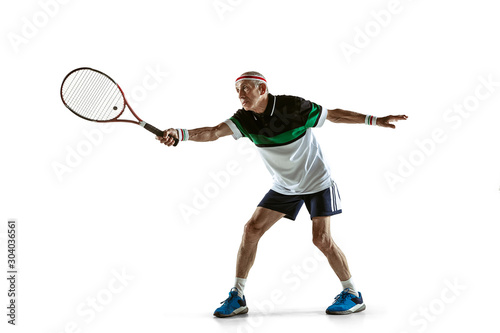 Senior man wearing sportwear playing tennis isolated on white background. Caucasian male model in great shape stays active and sportive. Concept of sport, activity, movement, wellbeing. Copyspace, ad.