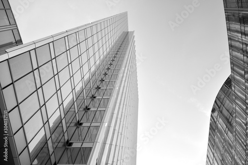 Modern office building wall made of steel and glass with blue sky. Black and white.