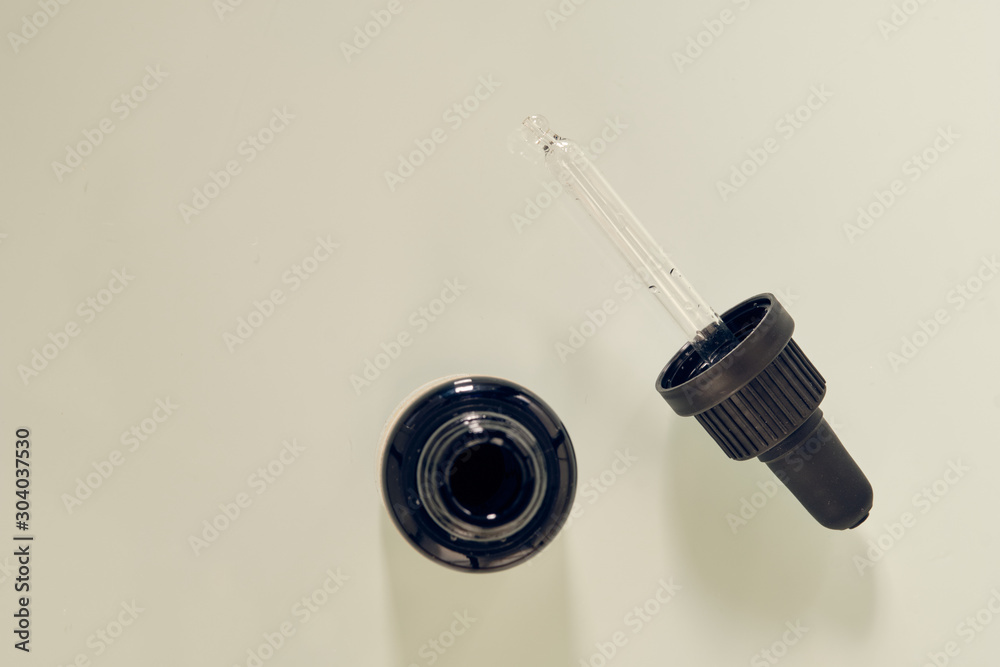 Pipette made of glass with black hold lying on white background. This pipette is made for a vitamin D3 supplement. Pipette made of glass with black hold lying on white background. This pipette is made for a vitamin D3 supplement.