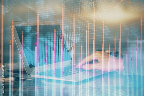 Double exposure of businessman's hands with laptop and stock market graph background. Concept of research and trading. © peshkova