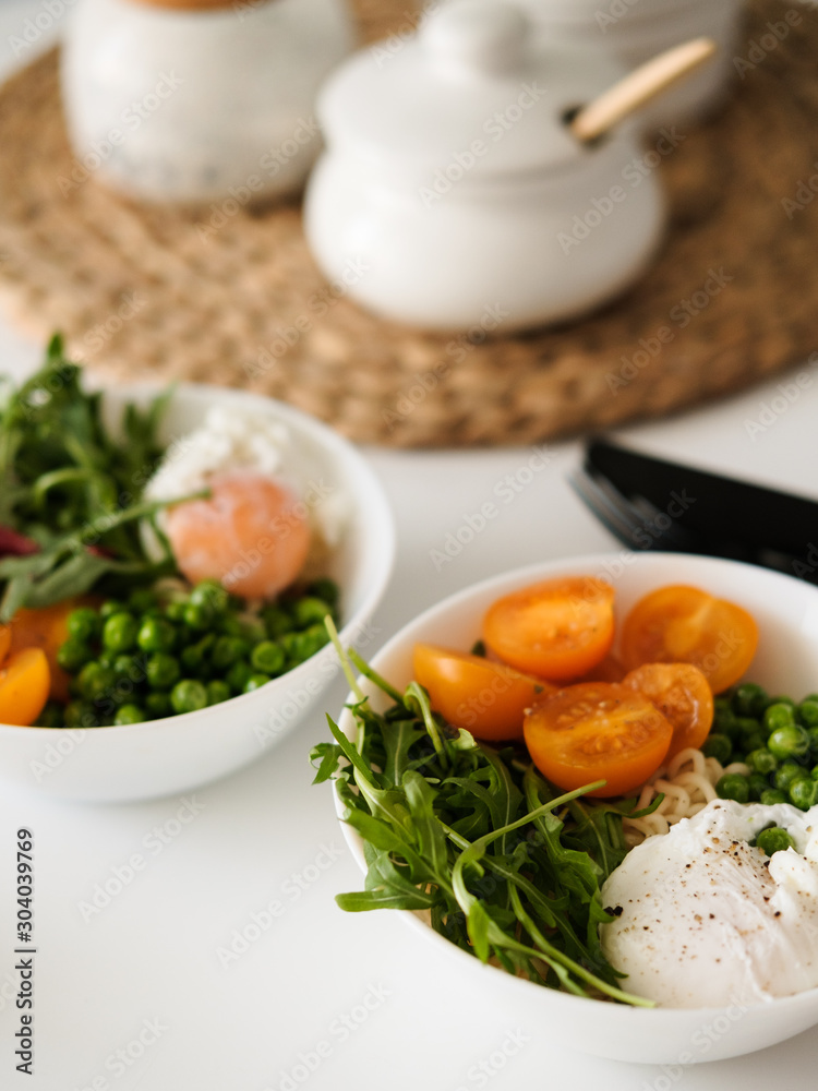 Salad with tomatoes, arugula, green peas and poached egg. A delicious and healthy lunch for two.