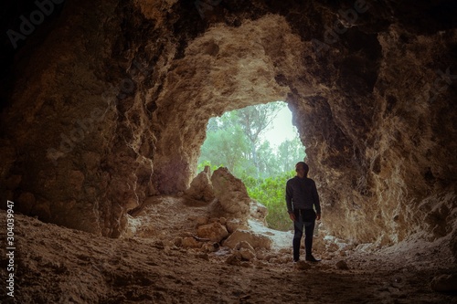 Young man inside a cave posing with jeans and a jacket