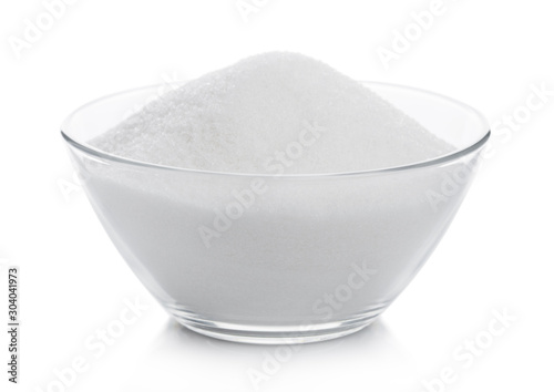 Glass bowl of natural white refined sugar on white background.