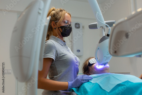 Beautiful woman-dentist bleaches the teeth to the patient
