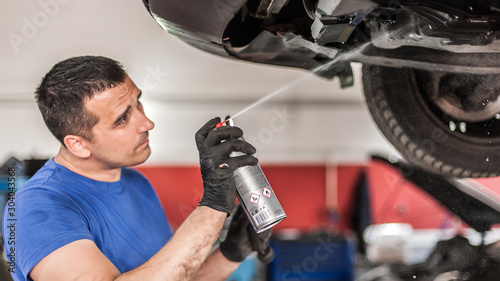 Fotografie Car master mechanic repairer lubricates screws with machine cleaner spray