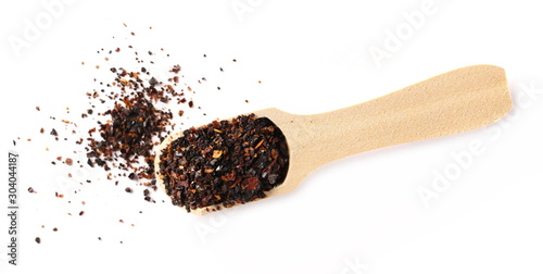 Dry red chili pepper flakes, cut up paprika with wooden spoon isolated on white background, top view