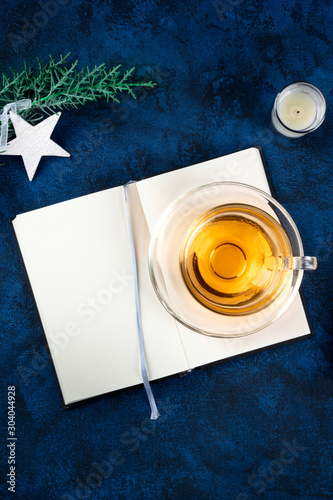 New Year's resolutions or bucket list concept, a flat lay top shot mock-up with a place for text, on a dark blue background with a star, a candle, and a cup of tea