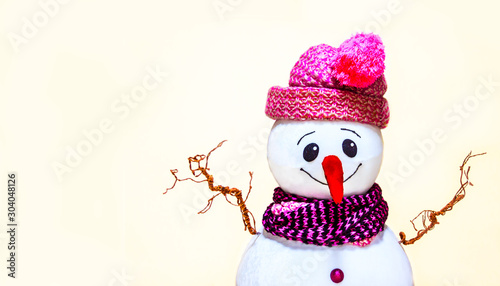 A cheerful portrait of a snowman, photographed as a portrait celebrates the New Year and Christmas holidays, raising his hands to the top, on a softly beige background with empty space for writing tex