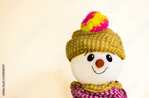 A cute and friendly muzzle of a snowman smiling wishes you a happy new year and Christmas on a pink background with empty space for writing text for the new year 2020.