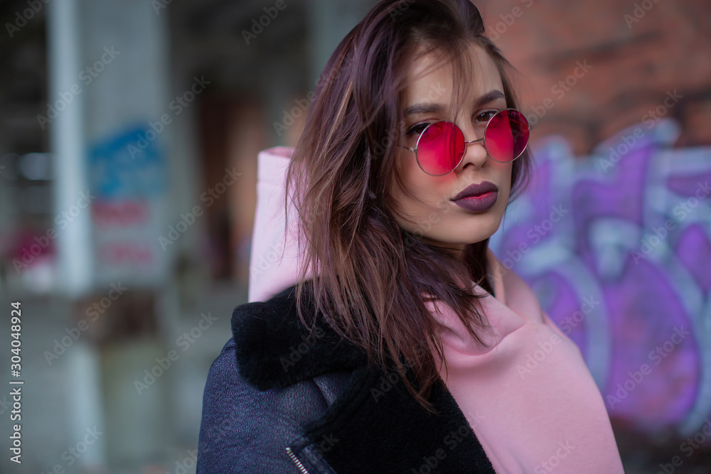 Portrait of a beauty girl who boldly looks into the camera from under colored red glasses Portrait of a beauty girl who boldly looks into the camera from under colored red glasses