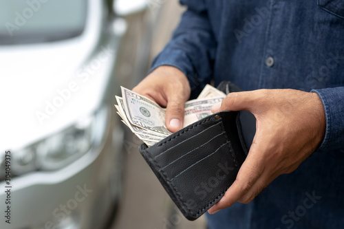 Businessman Person holding a wallet in the hands of take money out of pocket stand front car prepare pay by installments - insurance, loan and buying car finance concept insurance, payment a car photo