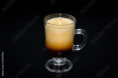 Very creamy espresso shot mug on black background 