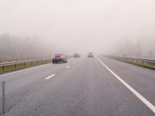 Blurred cars on a road in a fog, concept danger, driving in low visibility condition. © mark_gusev