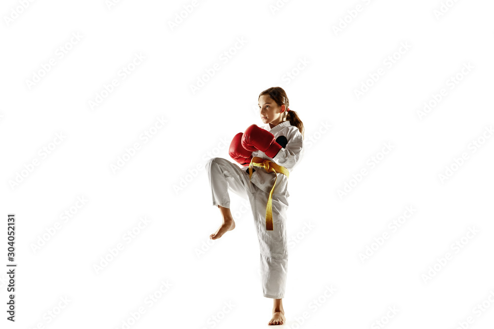 Confident junior in kimono practicing hand-to-hand combat, martial arts. Young female fighter with yellow belt s training on white studio background. Concept of healthy lifestyle, sport, action. Confident junior in kimono practicing hand-to-hand combat, martial arts. Young female fighter with yellow belt s training on white studio background. Concept of healthy lifestyle, sport, action.