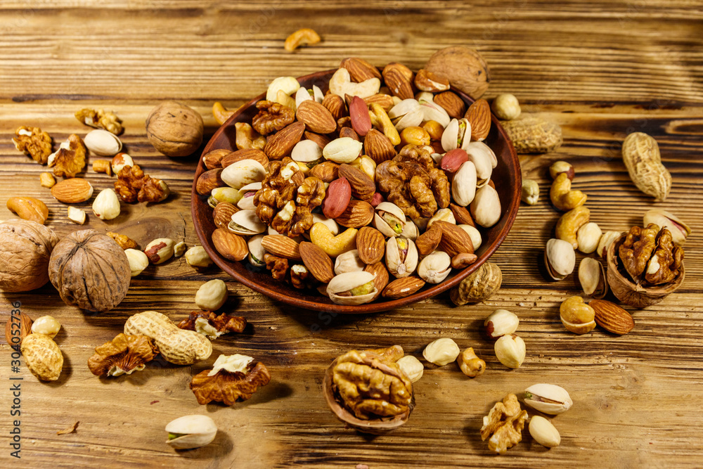 Mixed nuts on wooden table. Walnuts, pistachio, almond, peanut, cashew, hazelnut in ceramic bowl. Healthy eating concept Mixed nuts on wooden table. Walnuts, pistachio, almond, peanut, cashew, hazelnut in ceramic bowl. Healthy eating concept