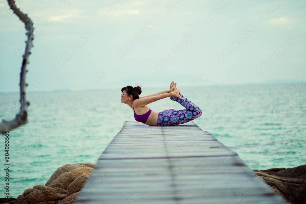 beautiful woman playing yoga in turtle pose on sea wooden pier beautiful woman playing yoga in turtle pose on sea wooden pier