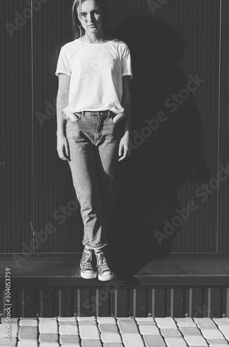 Black and white shot of Cropped portrait of Beautiful Woman against grey wall with Banana in the pocket of jeans