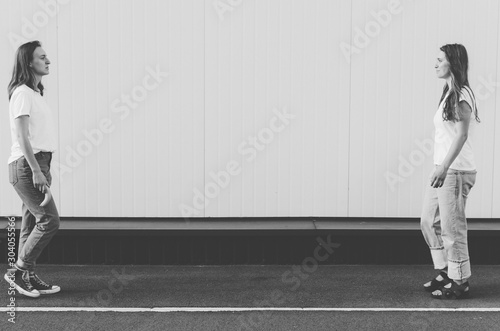 Black and white shot of Beautiful Women in white shirt and jeans holding banana like gun neare white wall photo