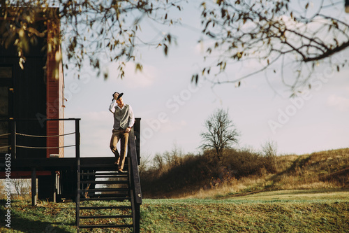 man in a hat on a background of a wooden house. nature in the background